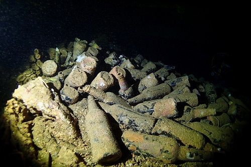 Piles of dusty beer bottles in a dark hold of the Hoki Maru wreck in Chuuk Lagoon, Micronesia