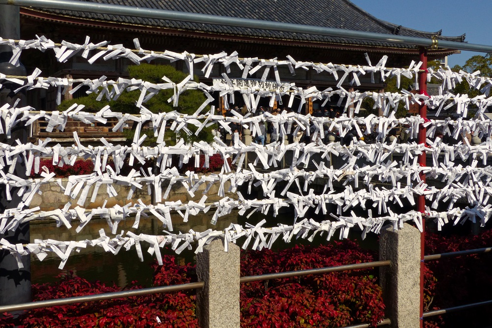 Rows of fortunes tied to fence at Shitennoji Temple in Osaka, Japan