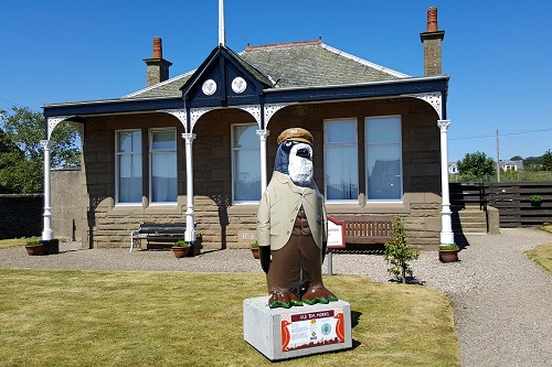 Penguin statue dressed as old man with beard in front of golf club, Carnoustie, Scotland