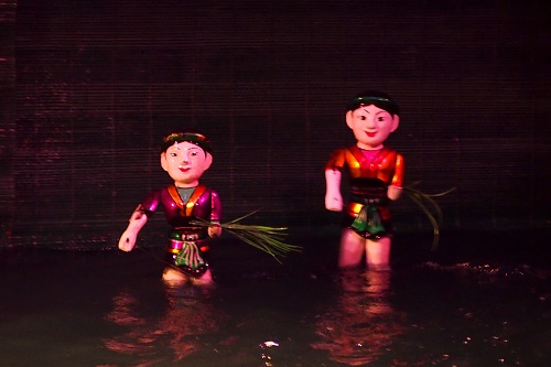 Two farmers carrying bundles of rice at Thang Long Water Puppet Theatre in Hanoi, Vietnam