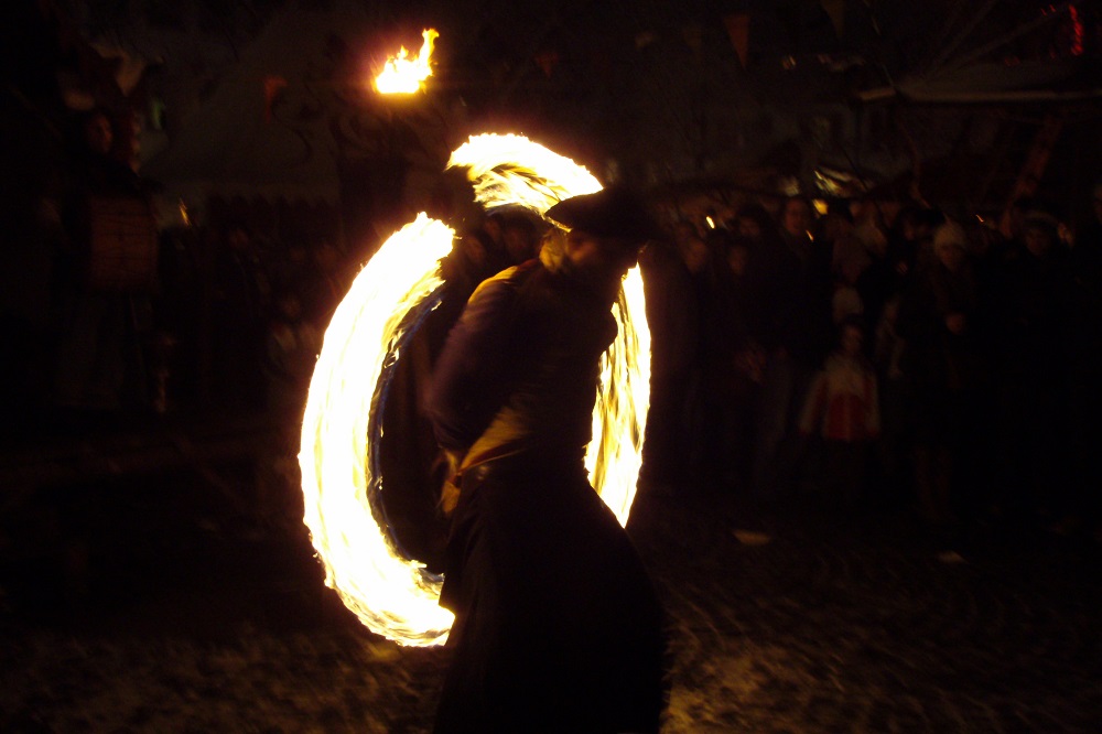 Fire dancer twirling flaming cannonball at Esslingen Medieval Market in Germany