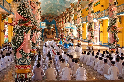 Rows of worshippers at Cao Dai Holy See temple in Vietnam