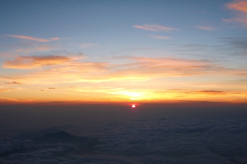 View of sunrise from Mount Fuji across clouds and smaller peaks