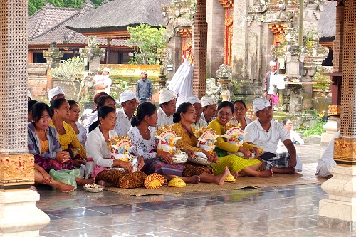 People sitting with offerings at ceremony at Ulun Danu Bratan temple in Bali, Indonesia