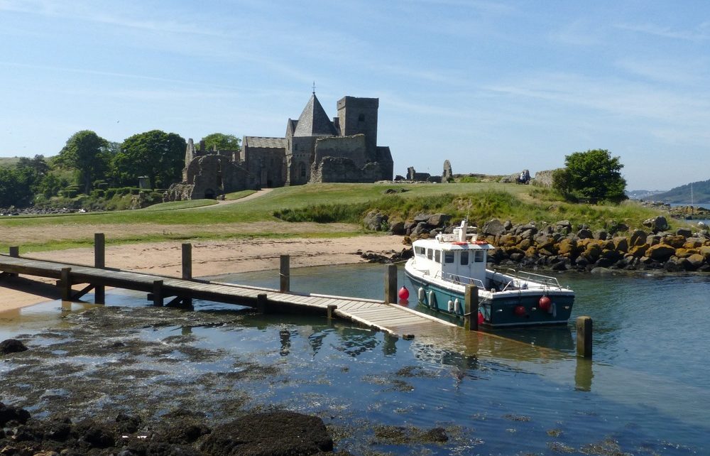 Boat at jetty with view of abbey on Inchcolm Island, Scotland